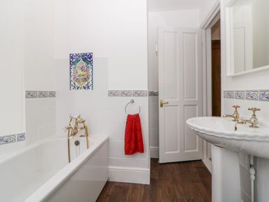 A bathroom with a bathtub sink mirror red towel and white door at Holcombe House in Torquay