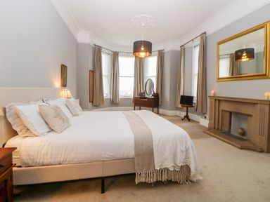 A bedroom with a bed a dressing table a fireplace and a mirror at Holcombe House in Torquay