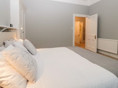 A bedroom with a white bed and pillows a door and a radiator on the wall at Holcombe House in Torquay