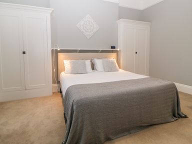 A bedroom with a bed with pillows and a blanket between two wardrobes at Holcombe House in Torquay