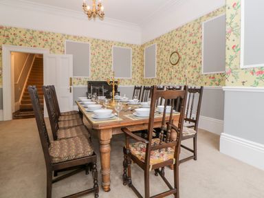 A dining room with a wooden table set with bowls and glasses surrounded by wooden chairs at Holcombe House in Torquay