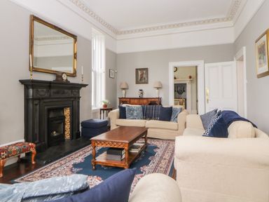 A living room with sofas and a wooden coffee table near a black fireplace at Holcombe House in Torquay