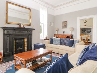 A living room with sofas cushions a wooden coffee table a fireplace and a sideboard with lamps at Holcombe House in Torquay