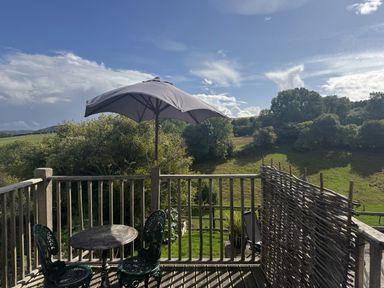An outdoor area with a table and chairs under an umbrella at The Hideout in Llangrove