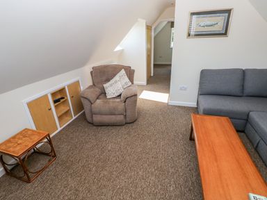 A living room with a brown armchair a grey sofa a wooden coffee table and a small wooden side table at Mill View in Neyland