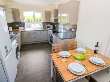 A kitchen with counters appliances and a dining table set for four at Mill View in Neyland