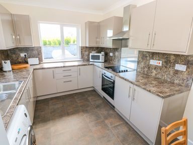 A kitchen with cabinets countertops a stove oven microwave and a window at Mill View in Neyland