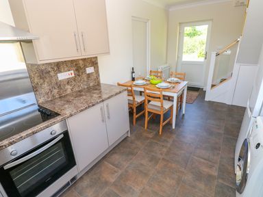 A kitchen with a dining table set for four people next to a door at Mill View in Neyland