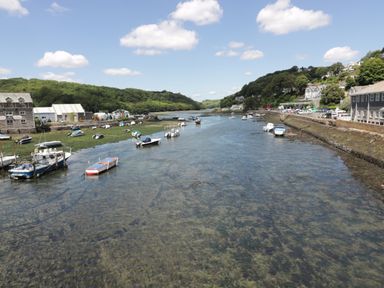 A river with small boats on both sides and buildings along the shore at Harbour View Apartment in Looe