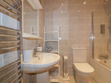 A bathroom with a sink mirror ladder shelf toilet and bathtub at Harbour View Apartment in Looe