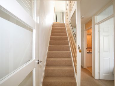 A staircase with carpet leading to an upper floor next to a hallway with doorways opening to other rooms at Delfryd in Y Felinheli