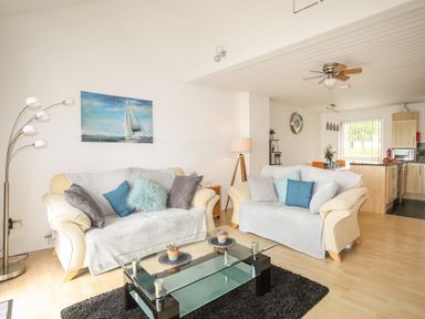 A living room with two sofas and a glass coffee table next to an open kitchen at Delfryd in Y Felinheli