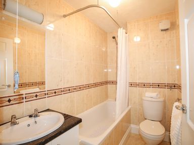 A bathroom with a sink countertop bathtub shower curtain and a toilet at Delfryd in Y Felinheli