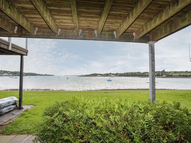 View of a body of water with boats and grassy area under a wooden deck at Delfryd in Y Felinheli