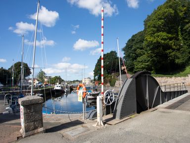 A canal with boats and a metal swinging bridge near trees at Delfryd in Y Felinheli