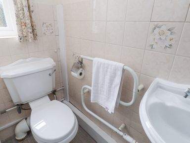 A bathroom with a toilet a white towel on a rail and a sink at Brackenbury Cottage in Beddgelert