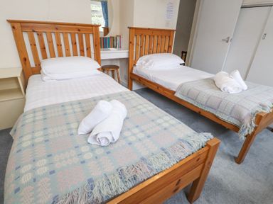 A bedroom with two single wooden beds with folded towels on the blankets at Brackenbury Cottage in Beddgelert