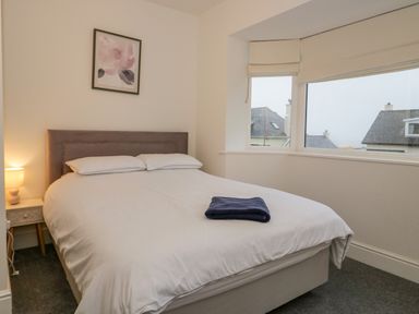 A bedroom with a bed pillow and blanket next to a window at Y Gogarth in Benllech