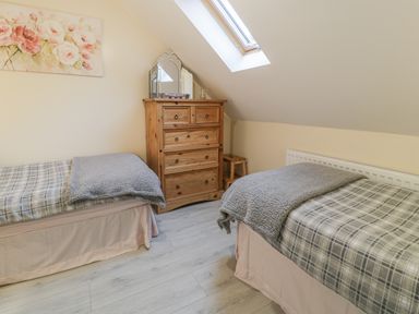 A bedroom with two single beds a wooden chest of drawers and a skylight window at Marchlyn in Deiniolen