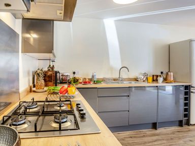 A kitchen with a gas stove fruits vegetables a sink toaster and a refrigerator at Marchlyn in Deiniolen