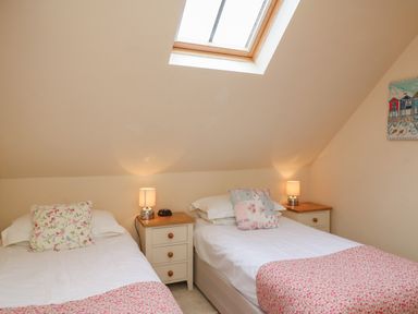 A bedroom with two single beds and bedside tables under a skylight at The Apple Barn at Wyke Farm in Lyme Regis
