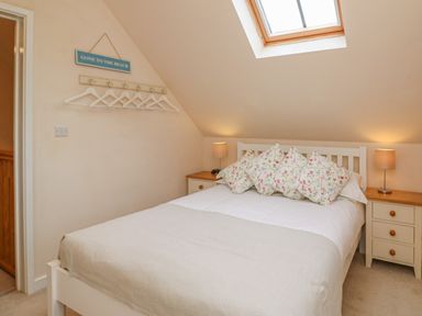 A bedroom with a bed with floral pillows and bedside tables with lamps at The Apple Barn at Wyke Farm in Lyme Regis