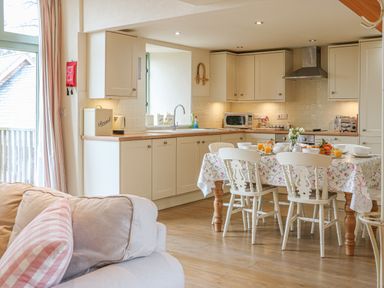 A kitchen and dining area with a table set for breakfast and a sofa in the foreground at The Apple Barn at Wyke Farm Lyme Regis