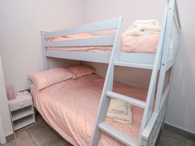 A bedroom with a white bunk bed with pink bedding and folded towels on the top and bottom beds at 201 Norton Park in Dartmouth
