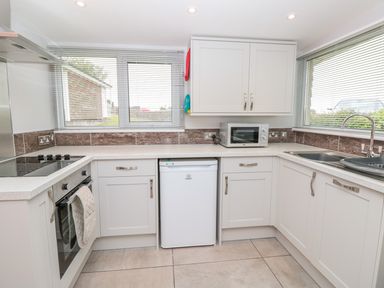 A kitchen with white cabinets a sink a microwave a small fridge and an oven at 201 Norton Park in Dartmouth