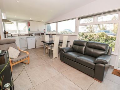 An open kitchen and dining area with a black leather sofa and beige chairs at 201 Norton Park in Dartmouth