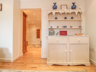 A wooden cabinet with shelves displaying blue pottery next to an open doorway showing a hallway at Church Road Annexe in Cinderford