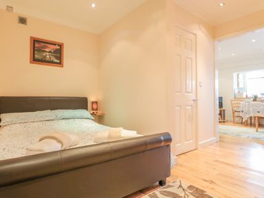 A bedroom with a double bed with folded towels bedside lamp a door and a view into a dining area at Church Road Annexe in Cinderford