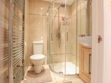 A bathroom with a toilet shower with glass doors a sink and a towel radiator at Church Road Annexe in Cinderford