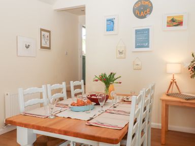 A dining room with a wooden table set with plates glasses and croissants and a vase of flowers at The Shippon at Wyke Farm Lyme Regis