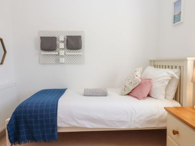 A single bed with pillows and a blue throw in a bedroom with wall decorations at The Shippon at Wyke Farm in Lyme Regis
