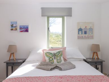 A bedroom with a bed two bedside tables with lamps and wall art at The Shippon at Wyke Farm Lyme Regis