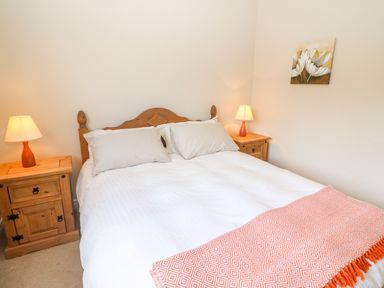 A bedroom with a wooden bed and two bedside tables with lamps at Sea View Hideaway in Lahinch County Clare