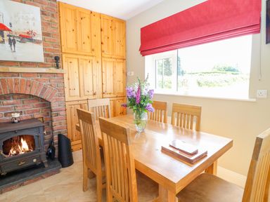 A dining area with wooden table and chairs a brick fireplace and built in wooden cabinets at Sea View Hideaway in Lahinch County Clare