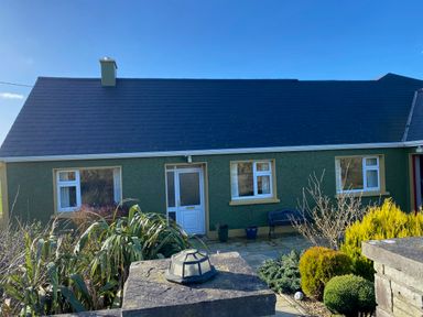A house with a green exterior and plants in front at Sea View Hideaway, Lahinch, County Clare