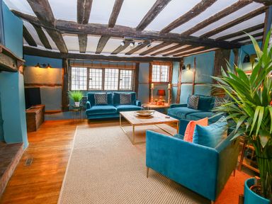 A living room with teal sofas wooden beams and a coffee table at 3 Masons Court in Stratford-Upon-Avon
