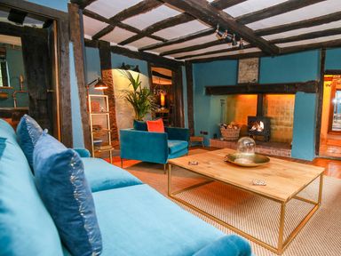 A living room with blue sofas a wooden coffee table a fireplace and exposed wooden beams at 3 Masons Court in Stratford-Upon-Avon