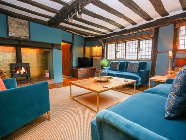 A living room with blue sofas a wooden coffee table and a fireplace at 3 Masons Court in Stratford-Upon-Avon