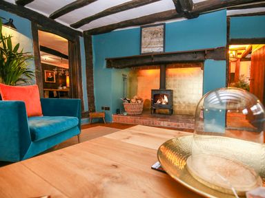A living room with a blue armchair and a fireplace with a wood stove at 3 Masons Court Stratford-Upon-Avon