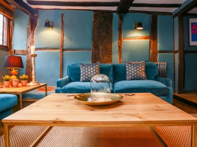 A living room with blue sofas wooden tables and decorative items at 3 Masons Court in Stratford-Upon-Avon