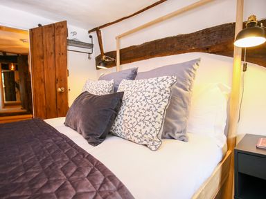 A bed with multiple pillows and a quilted blanket in a bedroom with wooden beams at 3 Masons Court in Stratford-Upon-Avon