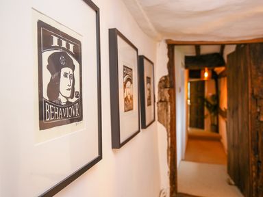 A hallway with framed pictures on the wall and wooden beams at 3 Masons Court in Stratford-Upon-Avon