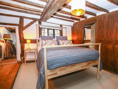A bedroom with a bed and nightstand with a lamp and a large mirror at 3 Masons Court Stratford-Upon-Avon