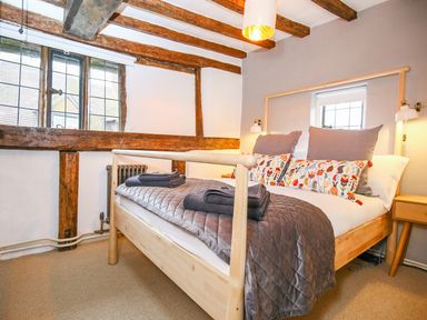 A bedroom with a wooden bed frame and folded towels on the bed at 3 Masons Court in Stratford-Upon-Avon
