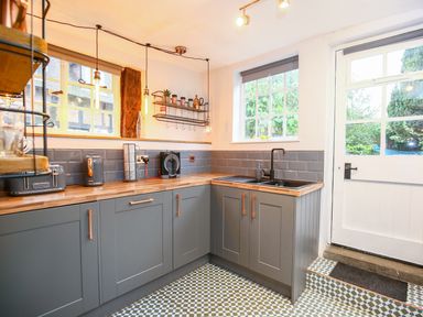 A kitchen with gray cabinets wooden countertops a black sink and a door with windows at 3 Masons Court Stratford-Upon-Avon