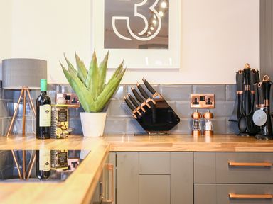 A kitchen countertop with a table lamp wine bottle plant knife set salt and pepper shakers and kitchen utensils at 3 Masons Court Stratford-Upon-Avon